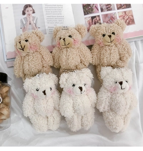 Flat lay of brown and white plush bear charms with bead chains on a magazine