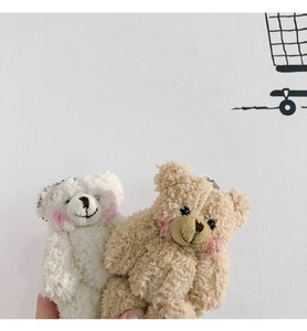 Detailed view of white and brown plush bear pendants with soft curly fur and blush