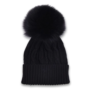 Close-up of black cable-knit beanie with a large matching faux fur pom-pom detail