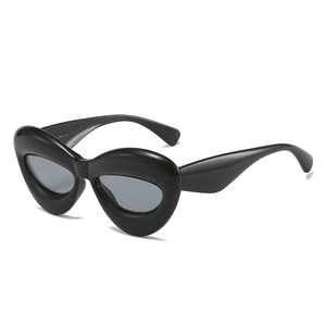 Lunettes de soleil noires surdimensionnées en forme de lèvres avec monture épaisse sur blanc