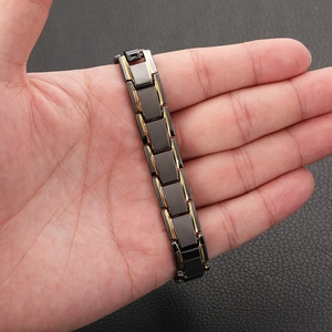Close-up of men's black and gold magnetic therapy bracelet on a wrist with leather background