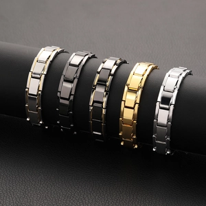 Five styles of men's magnetic steel bracelets in silver, gold, and black on a display