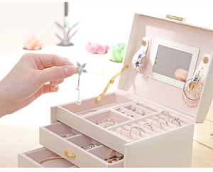 Detail of beige leather jewelry box with multi-layer drawers and soft pink velvet lining