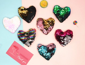 Detailed flat lay of heart-shaped sequin coin purses in multiple color options