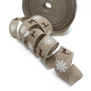 Close-up of burlap Christmas ribbon featuring white snowflakes and red reindeer patterns