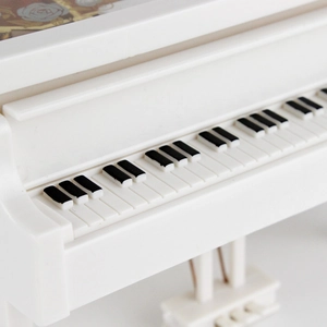 Elegant white miniature piano music box with detailed black and white keyboard layout