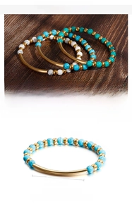 Detailed view of turquoise bead bracelet set with stainless steel tubes on wood surface