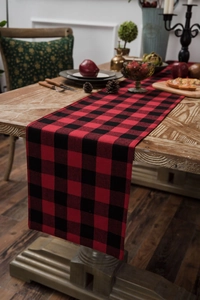 Close-up of red and black buffalo plaid table runner on a festive wooden dinner table