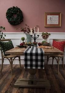 Detail of black and white plaid table runner with festive Christmas pillows on a wooden table