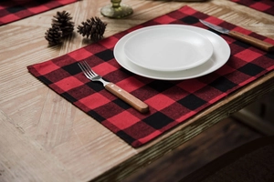 Macro detail of red and black plaid cotton linen placemats on a rustic wooden table