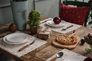 Close-up of festive cotton linen placemat with gold snowflake patterns on a wooden table