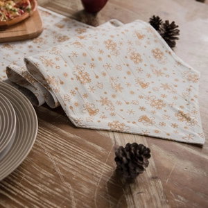 Christmas table runner with gold snowflake patterns on a rustic wooden dining table