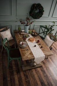 Festive table runner with orange snowflake pattern on a rustic wooden dining table