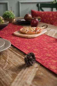 Close-up of red Christmas table runner with gold snowflake patterns on a wooden table