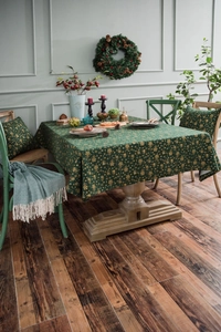 Detail of Christmas green tablecloth with golden tree patterns on vintage wooden table