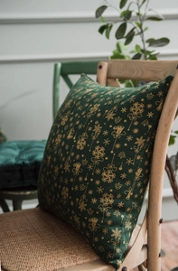 Detail of green Christmas cushion with golden bells and tree prints on wooden chair