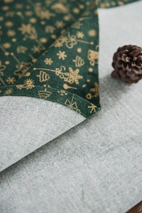 Detail of Christmas green tablecloth showing gold tree patterns and hemmed fabric edges