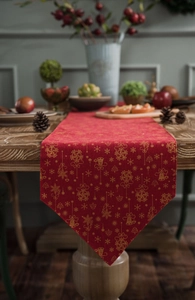 Detail of red Christmas table runner with golden snowflakes on dark wood table