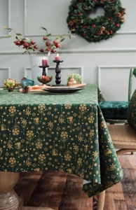 Detail of green and gold Christmas tablecloth featuring snowflake and tree patterns