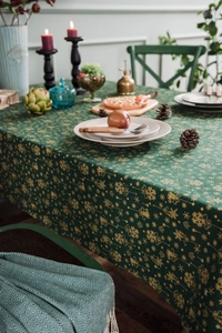 Detail of Christmas tablecloth with gold festive patterns on premium green fabric