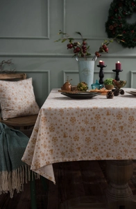 Detailed close-up of festive Christmas tablecloth with gold prints and holiday decor