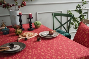 Detailed close-up of red Christmas tablecloth with golden snowflake and bell patterns