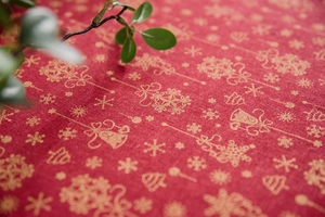 Close-up of red Christmas tablecloth with golden snowflakes and linen texture detail