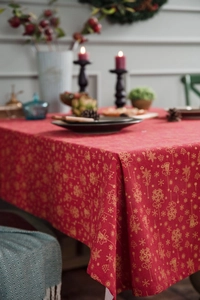 Detail of red Christmas tablecloth with golden snowflakes and festive bell prints