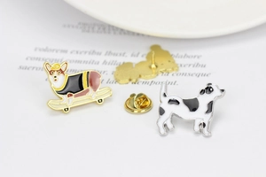 Close-up of enamel dog pins with a Corgi on a skateboard and butterfly clutch backs