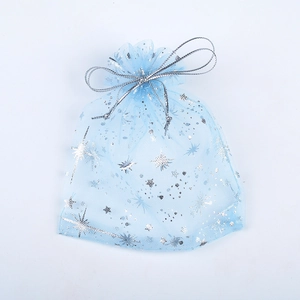 Close-up of light blue organza gift bag with silver star and snowflake patterns