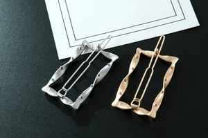 Detail of gold and silver rectangular hair clips with brushed metal texture and wavy edges