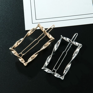 Detailed view of twisted rectangular hollow hair clips in polished gold and silver finishes