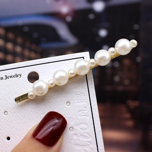 Macro shot of pearl bobby pin with gold metal base and staggered white pearls