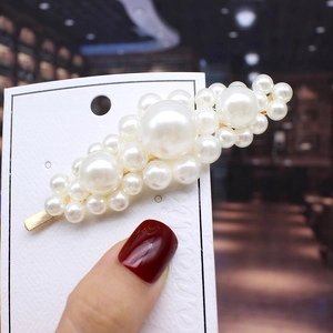 Macro shot of faux pearl hair clips set with gold-tone base on elegant display card