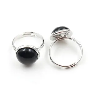 Macro detail of adjustable silver ring with round black onyx stone on white background