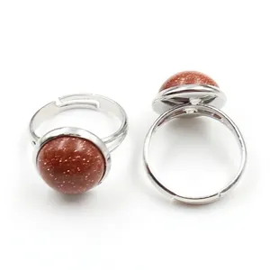 Close-up of adjustable silver rings with round red goldstone cabochons and glitter