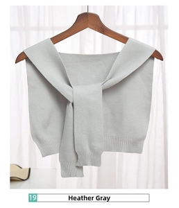 Close-up of mottled grey knitted shawl wrap with detailed rib texture on a wooden hanger
