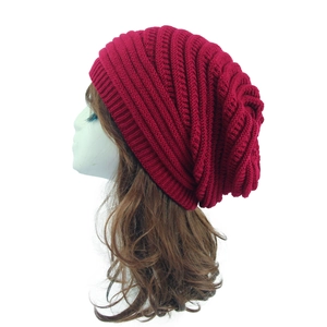Detail view of burgundy knitted slouchy beanie with thick yarn texture on a mannequin