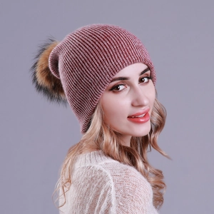 Detail of dusty pink ribbed knit beanie with a fluffy raccoon fur pom-pom on model