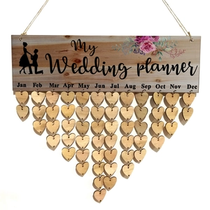 Macro view of wooden wedding planner calendar with hanging heart tags and floral pattern