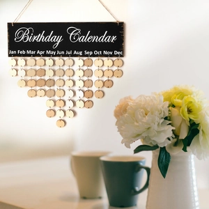 Detail of a black wooden birthday calendar plaque with hanging round month tags on a wall