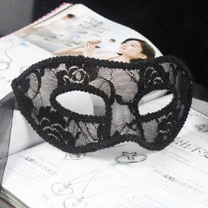 Detail of elegant black lace masquerade mask with intricate floral patterns and silk ribbons