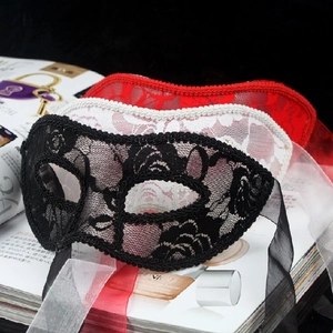Detailed texture of lace masquerade masks in black, white, and red with ribbon ties