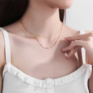 Minimalist gold double layer necklace shown worn on a model's collarbone and neck