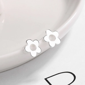 Macro shot of minimalist S925 sterling silver hollow five-petal flower stud earrings