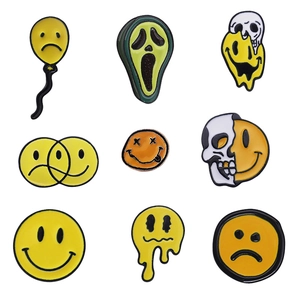 Set of nine cartoon skull and expressive face enamel pins in yellow and black metal