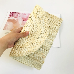 Detail view of the handmade corn husk woven texture on a straw clutch bag for women