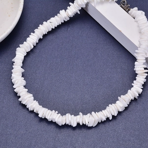 White irregular shell necklace set on grey background, layered choker style jewelry