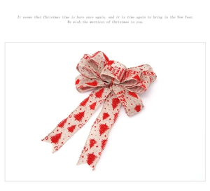Close-up of 25cm red burlap Christmas bow with tree patterns and holiday typography
