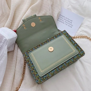 Green tweed crossbody bag with gold chain strap and leaf embroidery on white background